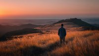 Man standing in golden grassland watching sunset over rolling hills creating peaceful contemplative moment for wellness and mindfulness concepts.