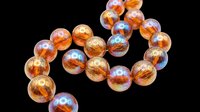 Iridescent amber glass beads arranged in a curved strand, isolated on transparent background, ready for jewelry, stickers, clipart, t-shirt design, and print on demand use.