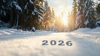 Snowy winter forest path with 2026 text shadow on fresh snow, sunlight breaking through pine trees at sunset creating magical atmosphere in woodland.