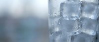 Close-up of ice cubes in a glass with water droplets and condensation, perfect for beverage, refreshment, and cold drink concepts.