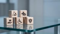 Healthcare insurance concept with wooden blocks displaying medical symbols on glass surface for business presentations and marketing materials.