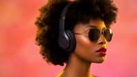 Stylish African American woman with afro hairstyle wearing sunglasses and headphones against vibrant coral background for music and lifestyle content.