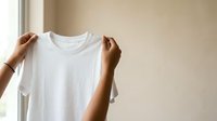White blank t-shirt held up by hands against neutral background, ready for design mockup, branding, or apparel customization projects.