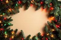 Festive Christmas border with glowing multicolored lights and evergreen pine branches framing beige background, creating holiday frame for seasonal designs.