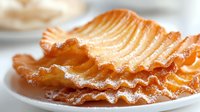 Golden crispy potato chips with wavy ridges stacked on white plate, close-up view showing crunchy texture and savory appeal for food photography.