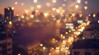 Romantic heart-shaped bokeh lights over blurred city street at sunset creating dreamy Valentine atmosphere for love themed designs and greeting cards.
