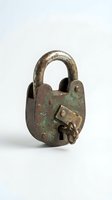 Antique brass padlock with ornate key isolated on white background, showing weathered patina and aged metal texture for security and vintage design concepts.