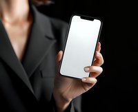 Businesswoman in formal black suit holding smartphone with blank white screen, showcasing elegant manicure and professional appearance.