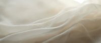Soft flowing fabric waves in cream and beige tones creating elegant textile background with gentle curves and subtle lighting for luxury design projects.