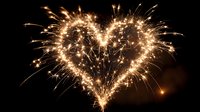 Golden sparkler fireworks forming romantic heart shape against dark night sky for celebration events and wedding ceremonies.