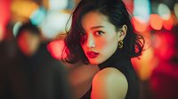 Young Asian woman with red lips and earrings against colorful bokeh city lights background at night for fashion and beauty concepts.