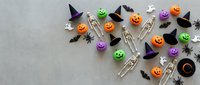 Colorful Halloween party decorations with pumpkins, ghosts, witches hats, bats and spiders arranged on gray background for festive seasonal celebrations.