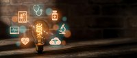 Glowing vintage light bulb surrounded by floating medical healthcare icons on wooden surface representing innovation in medicine and technology solutions.