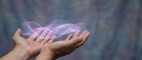 Cupped hands holding glowing purple energy waves against soft blurred background for healing, spirituality and wellness concepts.