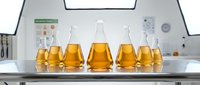 Golden amber liquid in laboratory flasks arranged on white counter in modern research facility. Scientific testing and chemical analysis setup for educational or industrial purposes.