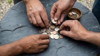 Multiple hands of diverse individuals arranging coins on slate surface, representing financial planning, savings, investment strategy, and collaborative wealth management for business concepts.