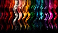 Vibrant wavy strands of multicolored hair arranged in rainbow spectrum from red to purple on black background, showcasing modern hair coloring trends and styles.