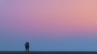 Romantic couple silhouette embracing against dreamy purple pink gradient sky at sunset creating intimate moment for love and relationship concepts.