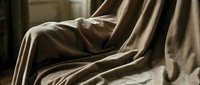 Luxurious beige silk fabric with elegant folds and drapes, showcasing smooth texture and natural light reflections for luxury design projects.