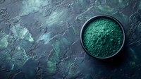 Green spirulina powder in black ceramic bowl on dark textured background with copy space. Natural superfood and healthy eating concept.