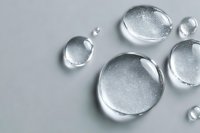 Clear water droplets on gray surface with realistic reflections and transparency effects for cosmetic and skincare product backgrounds.
