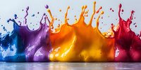 Colorful liquid paint splashes in blue, purple, orange and red creating dynamic crown-shaped formations against light background, captured in high-speed photography.