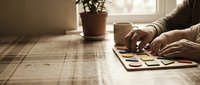 Person using calculator at wooden table with coffee cup and plant in warm sunlight for financial planning and budgeting tasks.