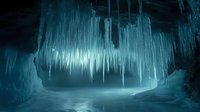Frozen underground cavern with massive icicles hanging from ceiling and walls, creating ethereal blue-toned atmosphere. Suitable for fantasy, sci-fi, and winter-themed design projects.