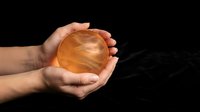 Hand holding glowing amber sphere against dark background, symbolizing energy, power, innovation, and future technology concepts for business and design projects.