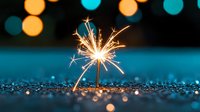 Glowing sparkler against dark turquoise background with bokeh lights and glitter surface creates magical festive atmosphere for celebration and holiday designs.
