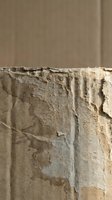 Weathered concrete wall with peeling paint and exposed layers showing age and deterioration in natural lighting for construction renovation projects.