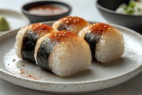Traditional onigiri rice balls with nori seaweed wrap and spicy seasoning served on ceramic plate. Japanese cuisine close up with selective focus.