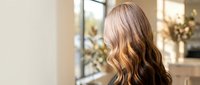Young blonde woman with wavy hair in modern salon interior with natural lighting and elegant decor for beauty and haircare services.