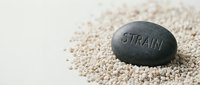Smooth black stone with engraved text resting on light beige sand or gravel, symbolizing stress relief, mindfulness, and wellness practices for meditation and relaxation.