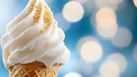 Creamy vanilla soft serve ice cream swirled on waffle cone with golden sprinkles against blurred blue bokeh background, sweet summer dessert treat for food advertising.