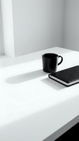 Black mug and notebook on white desk in minimalist workspace. Monochrome office setup for business, productivity, and creative work concepts.