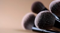 Professional makeup brushes with soft synthetic bristles in close-up view against blurred neutral background, highlighting texture and quality for cosmetic application.