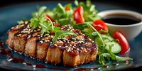 Grilled tofu steak with sesame seeds and fresh arugula salad on dark plate. Healthy vegan protein meal with soy sauce for plant-based dining and vegetarian cuisine.