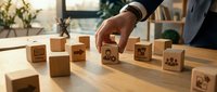 Business professional arranging wooden blocks with management icons on office desk, representing strategic planning and organizational development concepts.