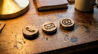 Wooden stamps with engraved communication symbols arranged on rustic desk surface with warm lighting, suitable for branding, contact concepts, and creative design projects.