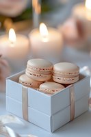 Delicate pink macarons in elegant white gift box with ribbon, soft candlelight creates romantic atmosphere for wedding favors or special celebration.