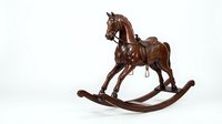 Vintage wooden rocking horse with leather saddle, isolated on white background. Antique handcrafted toy with rich brown finish for nursery decor.