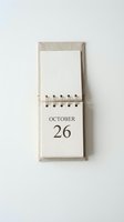 Spiral-bound desk calendar with linen cover displaying October 26 date on cream paper, blank page above for notes and planning.