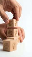 Hands stacking wooden blocks engraved with brain and light bulb icons, symbolizing creativity, innovation, and smart thinking in business.