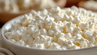 Fresh popcorn in white ceramic bowl, extreme close up with selective focus showing fluffy kernels and detailed texture, natural lighting creates soft shadows.