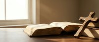 Open bible with wooden cross on table in warm sunlight streaming through window creating peaceful spiritual atmosphere for prayer and meditation.