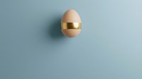 Single brown egg with golden metallic band floating on soft blue background for luxury food branding and premium organic product marketing campaigns.