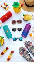 Summer vacation essentials flat lay with sunglasses, speakers, flip flops, straw hat and tropical drinks on white background for travel lifestyle design.