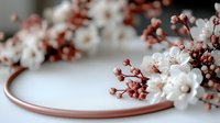 Delicate white gypsophila and coral pink baby's breath flowers arranged on round copper frame against white background, creating soft romantic composition.