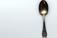 Vintage ornate spoon with gold-toned bowl and decorative silver handle isolated on white background, suitable for tableware design, culinary content, and dining concepts.